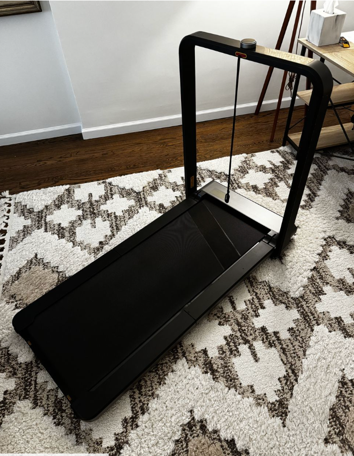 a black under desk treadmill in a home on a patterned rug
