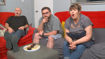 a group of people sitting on a couch with a plate of food