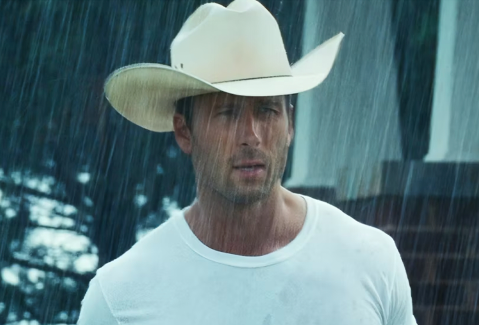 glen powell wearing a white hat and white tshirt in rain