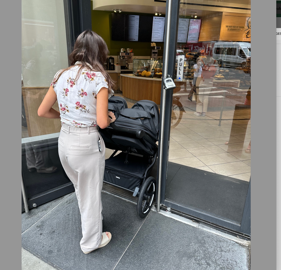 a tester from the good housekeeping institute pushes a double stroller from thule through the door of a panera restaurant