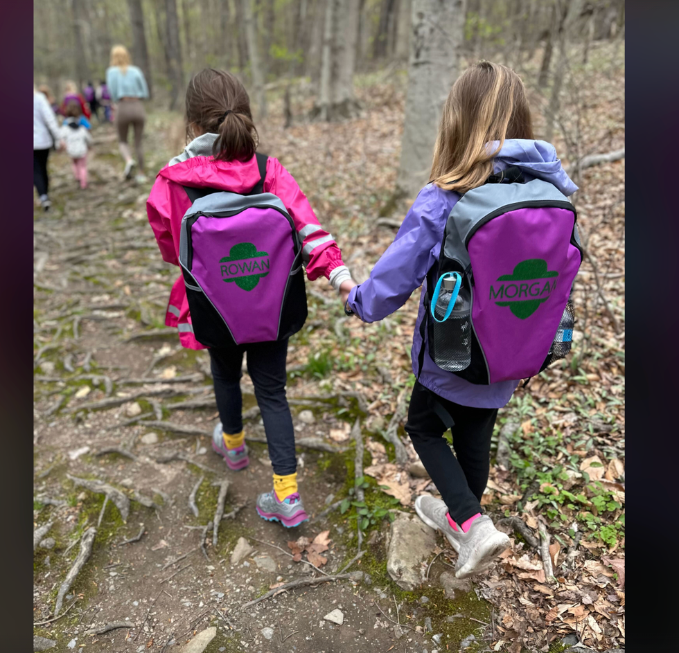 a child wears purple and gray merrell walking shoes on a hike with friends