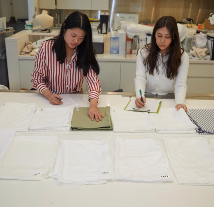 two testers touching sheets in the textiles lab to rate them for softness