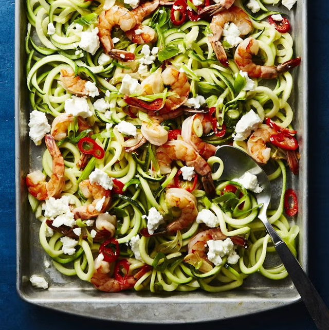 a baking tray filled with spiralized zucchini noodles topped with cooked shrimp a baking tray filled with spiralized zucchini noodles topped with cooked shrimp
