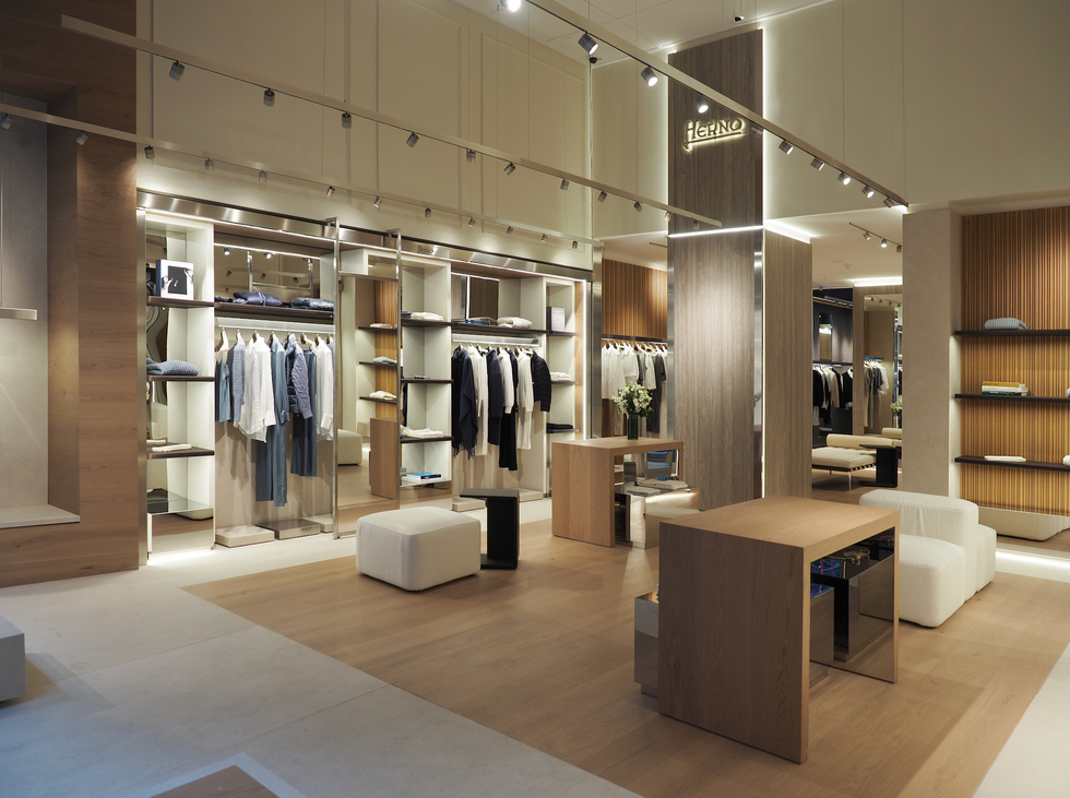 a modern fashion retail store with racks of neatly arranged clothing, including shirts and jackets, showcased within well lit displays