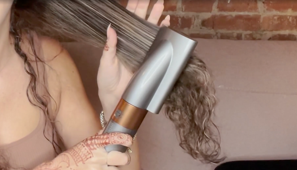 a person uses a hair styling tool to style their hair