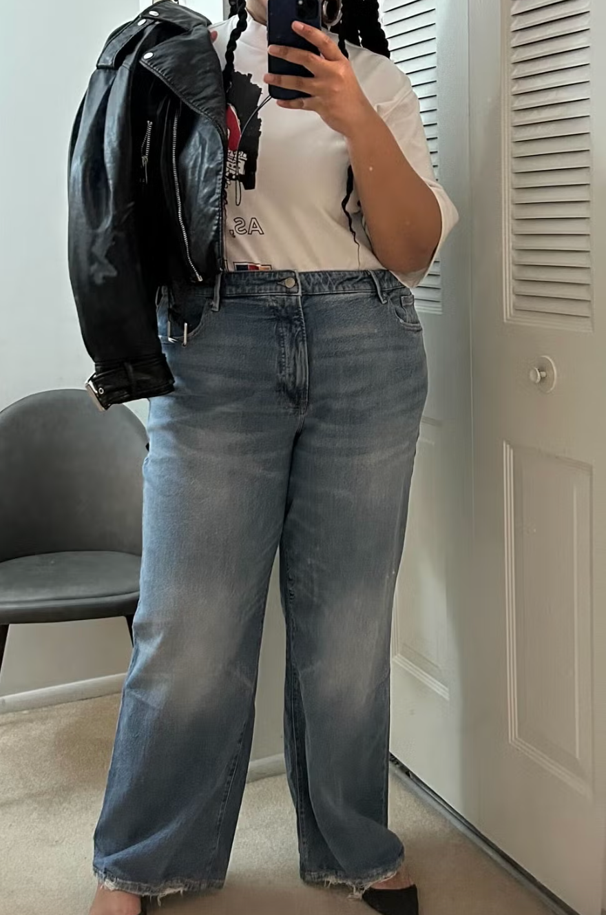 a woman modeling a pair of jeans from good american with a closet in the background