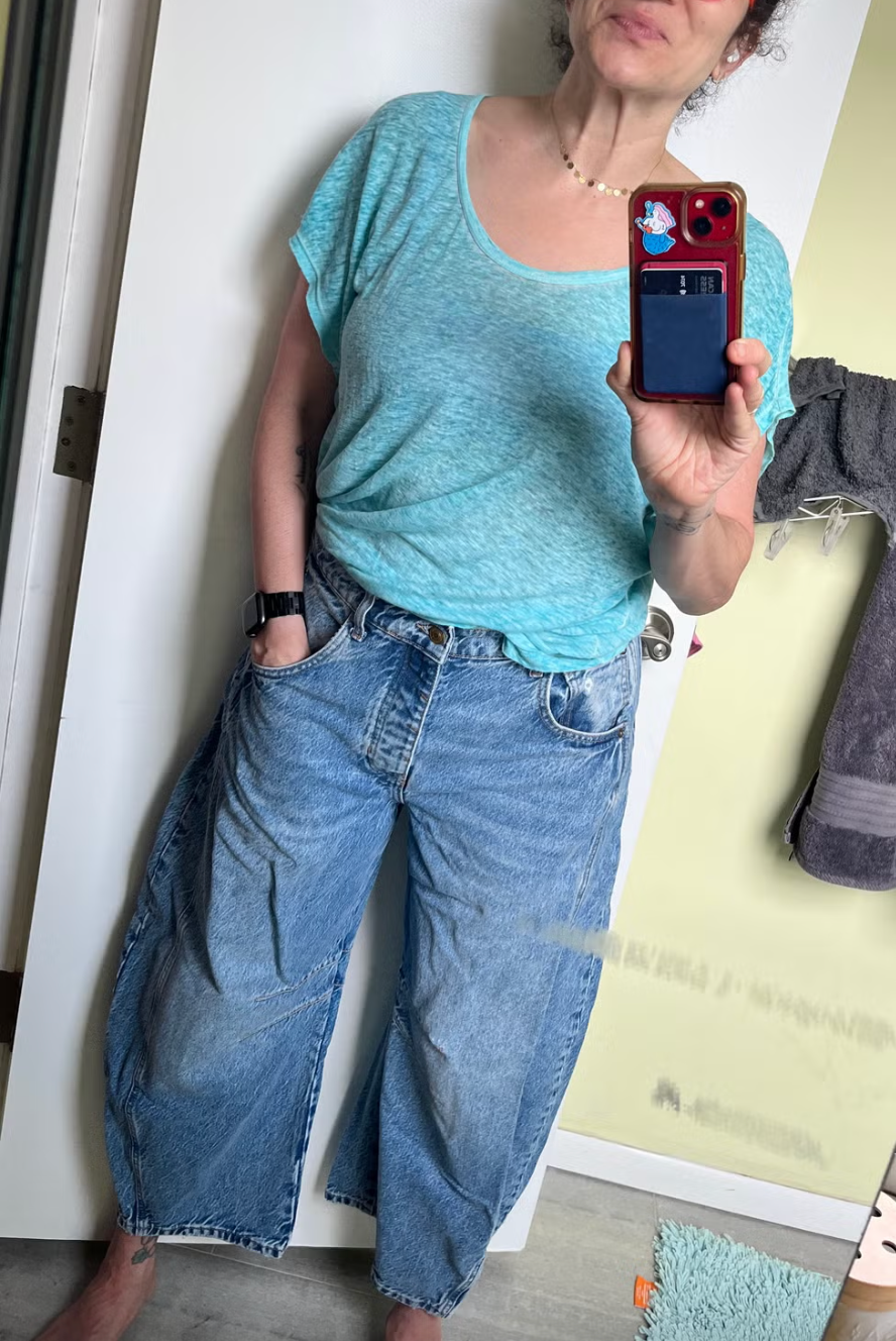 a woman modeling barrel jeans from free people against a bathroom wall
