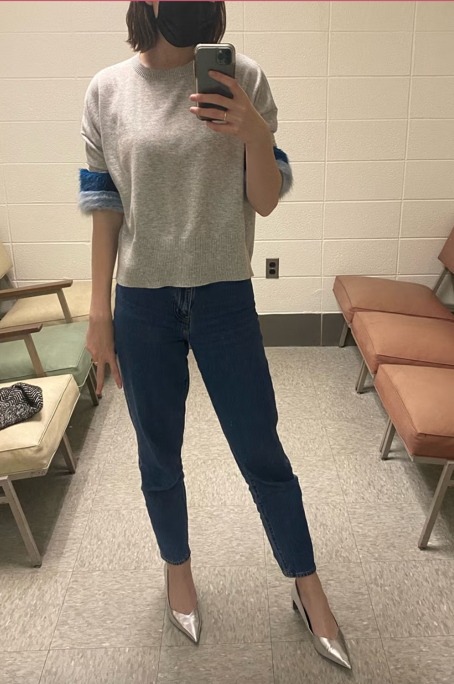 a person modeling jeans from everlane in a powder room seated area