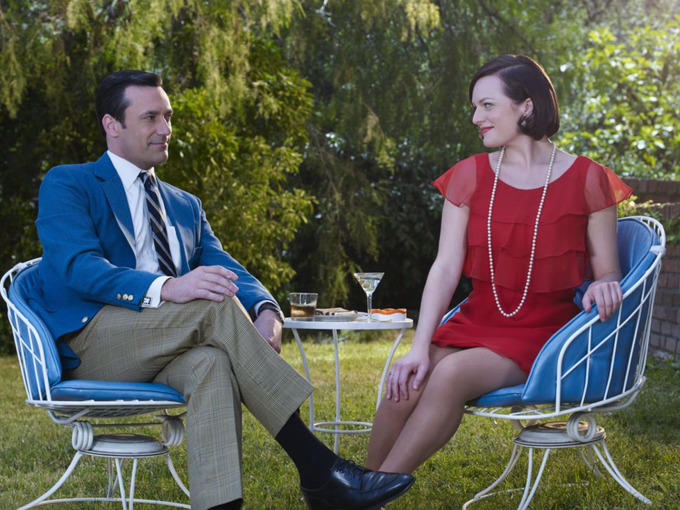 two individuals are seated outdoors on blue and white metal chairs