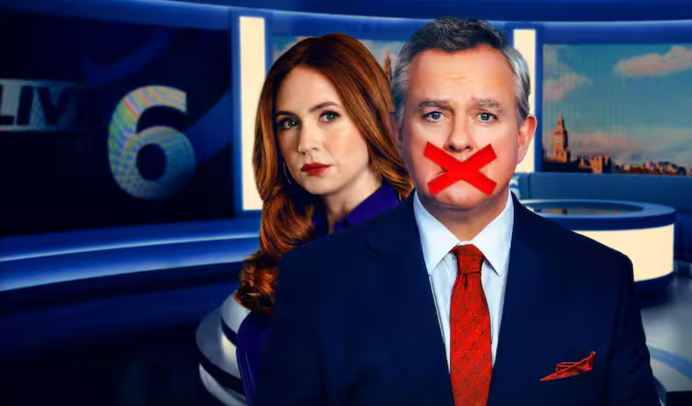 two news anchors are positioned in a television studio, with one in front and the other slightly behind