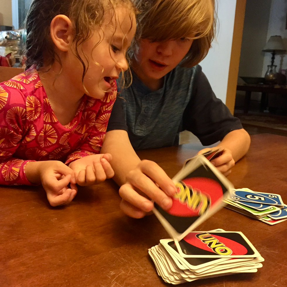 playing Uno on a family vacation a girl and boy in their swim shirts play a game of uno