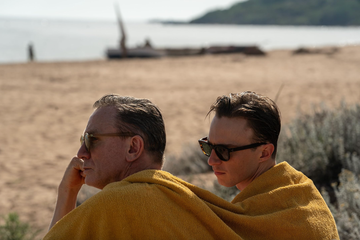 two individuals wrapped in yellow towels sitting on the beach