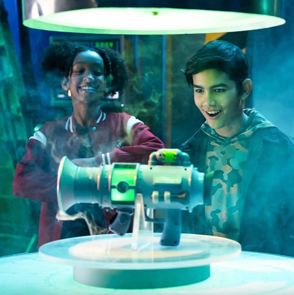 two kids standing with a fart blaster toy