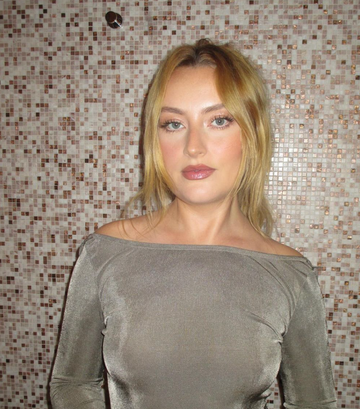 a person standing against a tiled wall wearing a gray offshoulder top