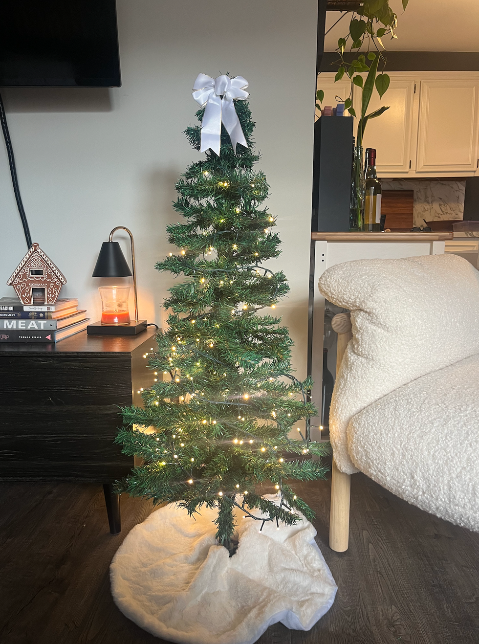 decorated christmas tree with lights and a bow in a cozy living space