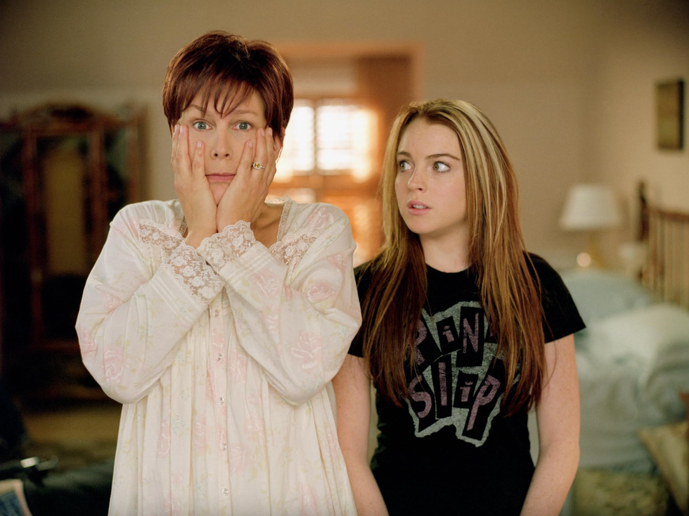 two individuals standing in a room one in nightwear and the other in a graphic tshirt