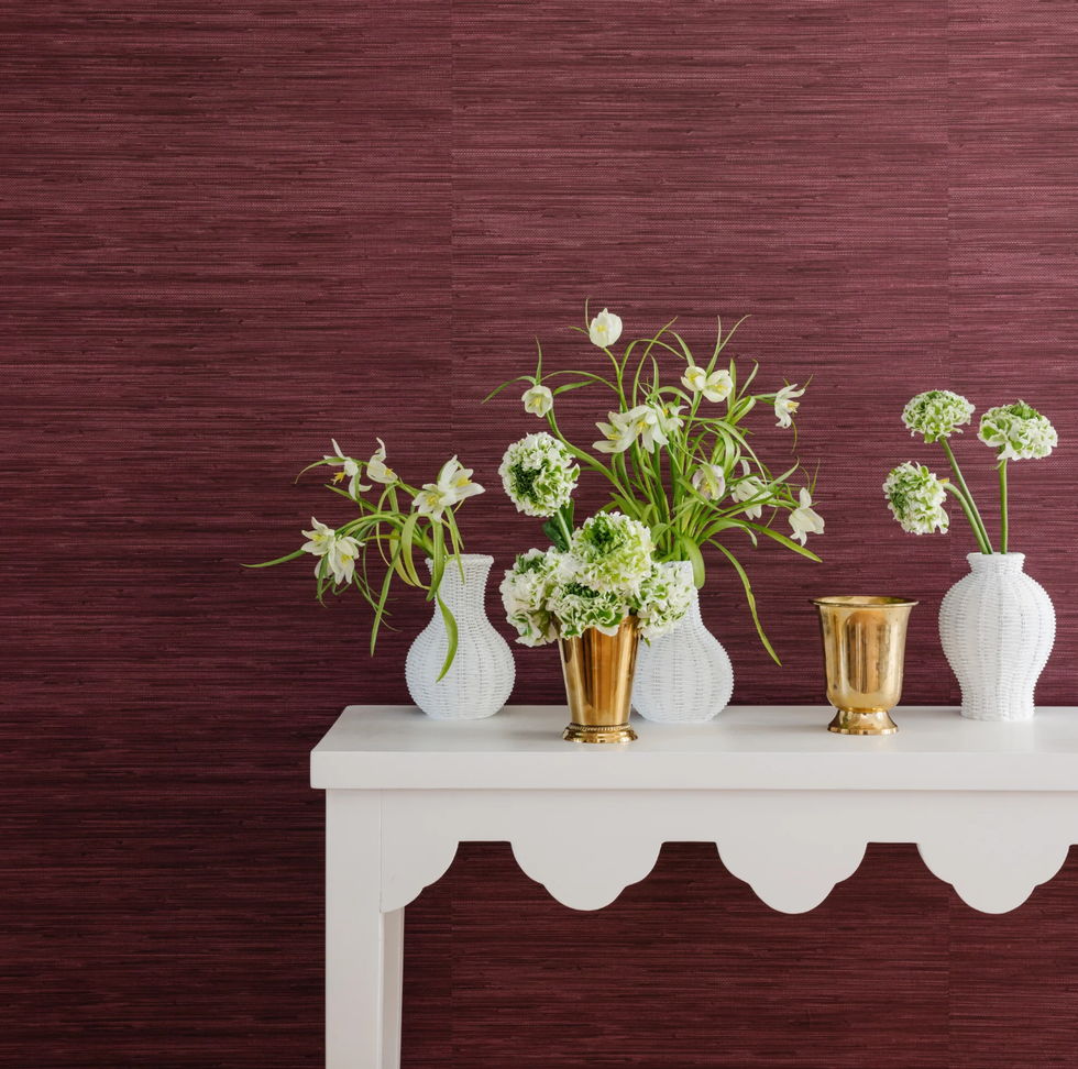 arrangement of flowers in decorative vases on a white table against a textured purple wall