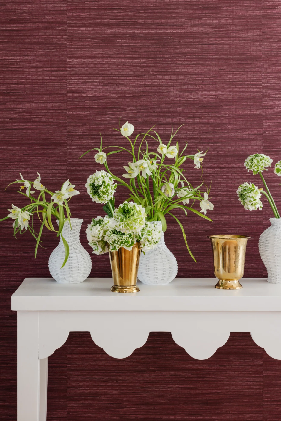 arrangement of flowers in decorative vases on a white table against a textured purple wall arrangement of flowers in decorative vases on a white table against a textured purple wall