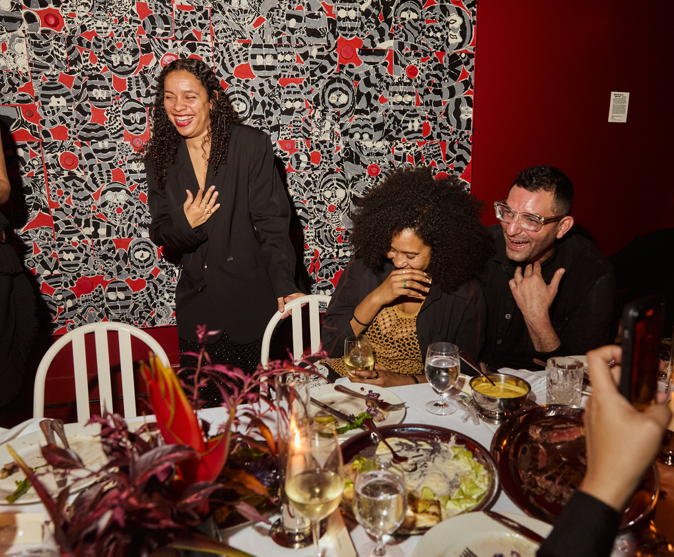 group of people gathered around a dining table with food and drinks