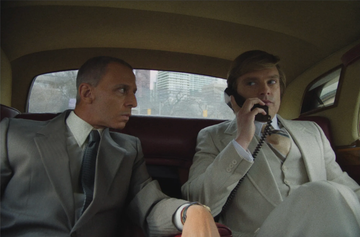 two men seated in a luxury car engaged in conversation