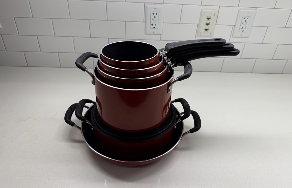 stacked cookware including pots and a frying pan on a countertop