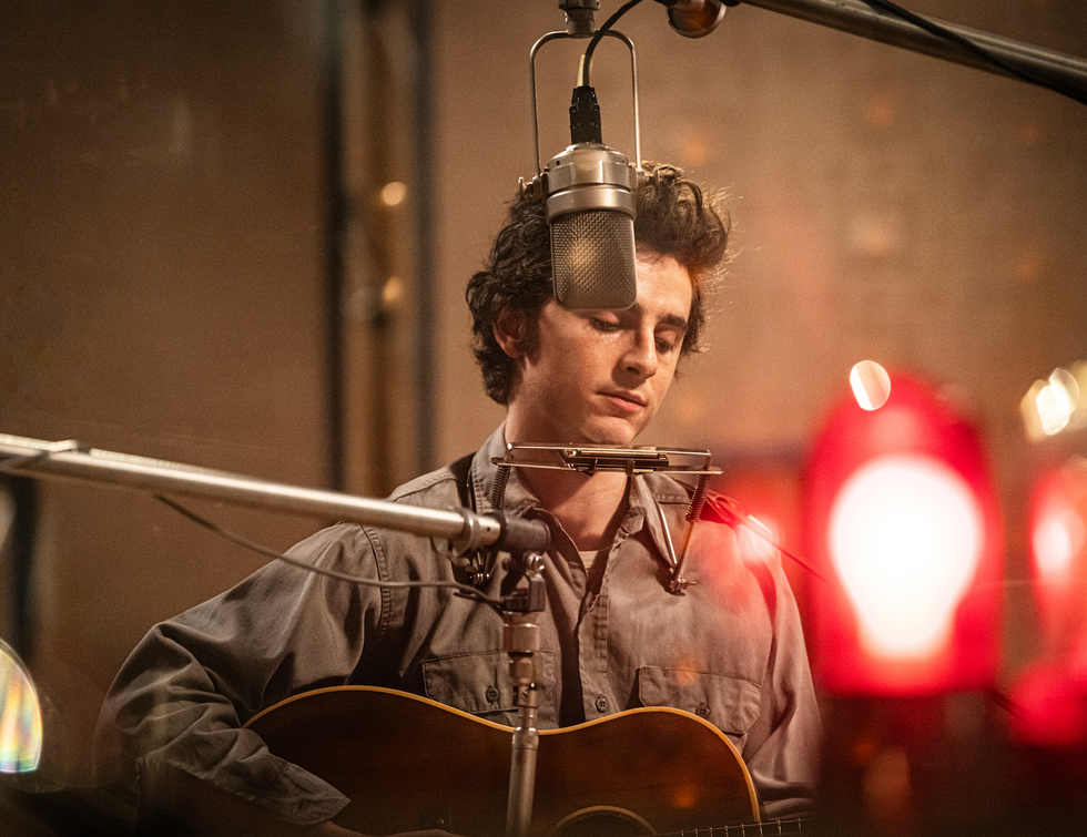 musician performing with an acoustic guitar in a studio setting