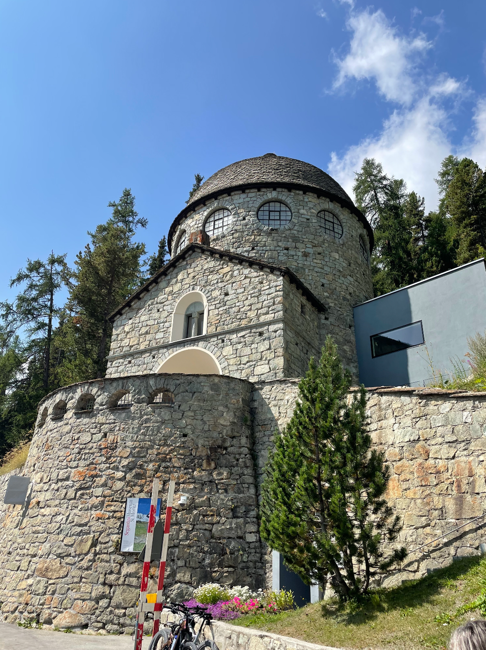 historical stone building with a rounded roof and surrounded by trees