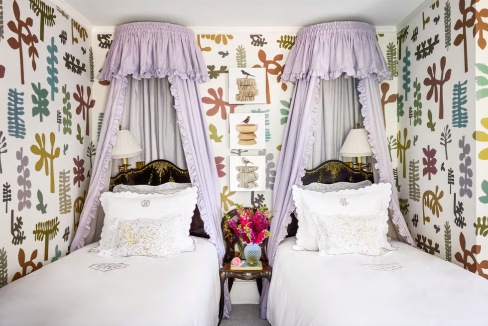 two twin beds with a decorative canopy and colorful wallpaper in a bedroom