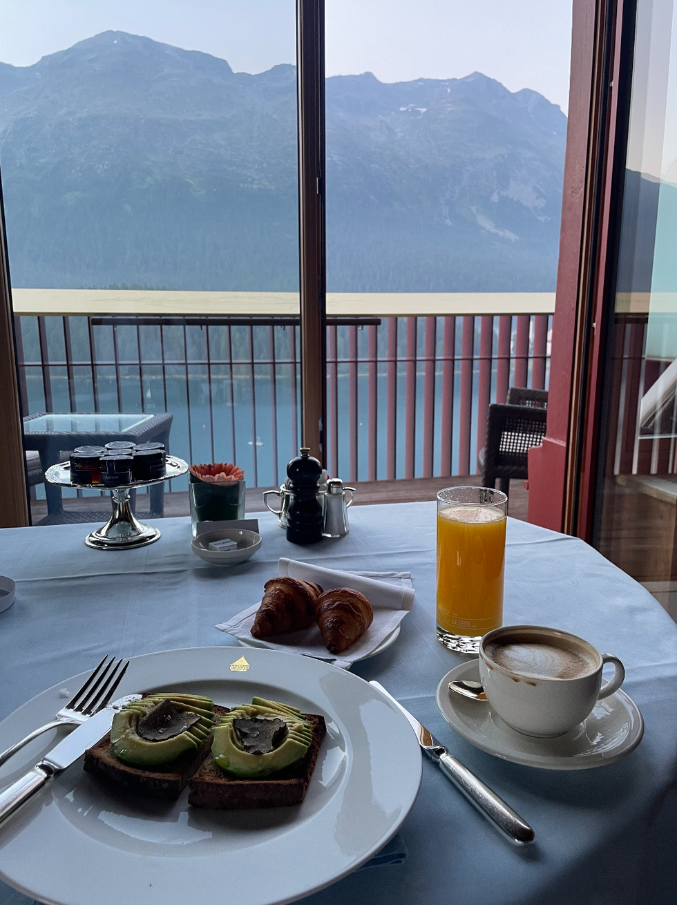 breakfast setting with avocado toast croissants coffee and orange juice overlooking mountains