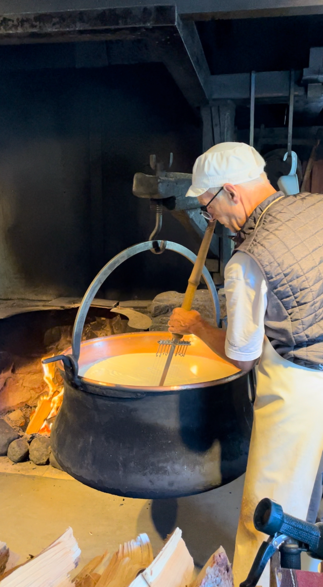 person stirring a large pot over an open flame