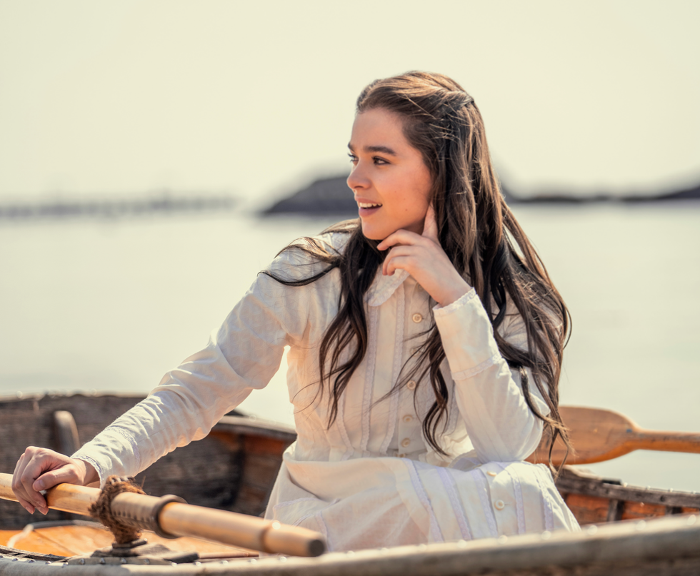 a person sitting in a boat holding a paddle and resting their chin on their hand