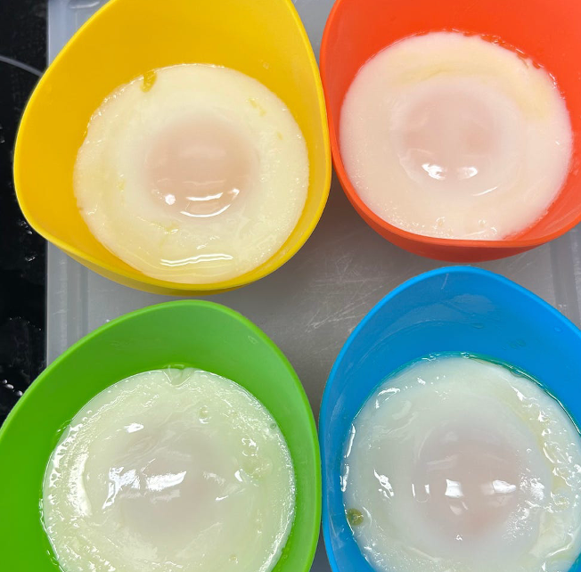 colorful silicone egg poachers containing cooked eggs