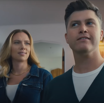 Scarlett Johansson and Colin Jost two individuals standing indoors appearing surprised or attentive
