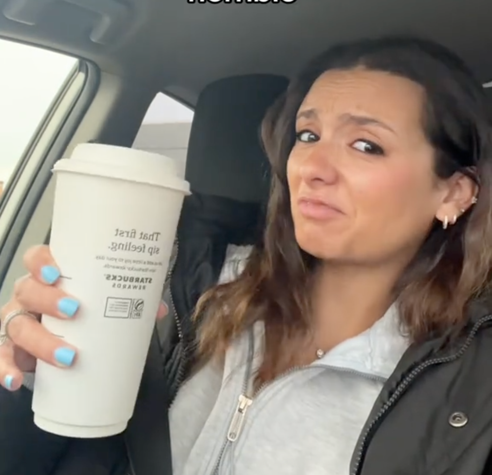 person holding a starbucks coffee cup inside a vehicle