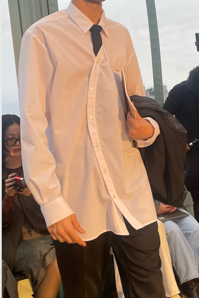 model showcasing a fashion outfit with an oversized white shirt and black pants model showcasing a fashion outfit with an oversized white shirt and black pants