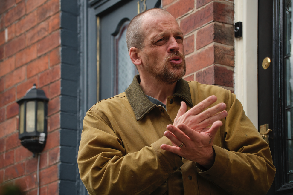 a man gesturing while standing in front of a door