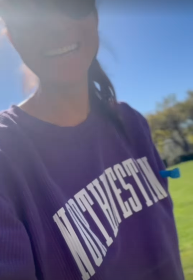 individual wearing a purple sweatshirt in a sunny outdoor setting