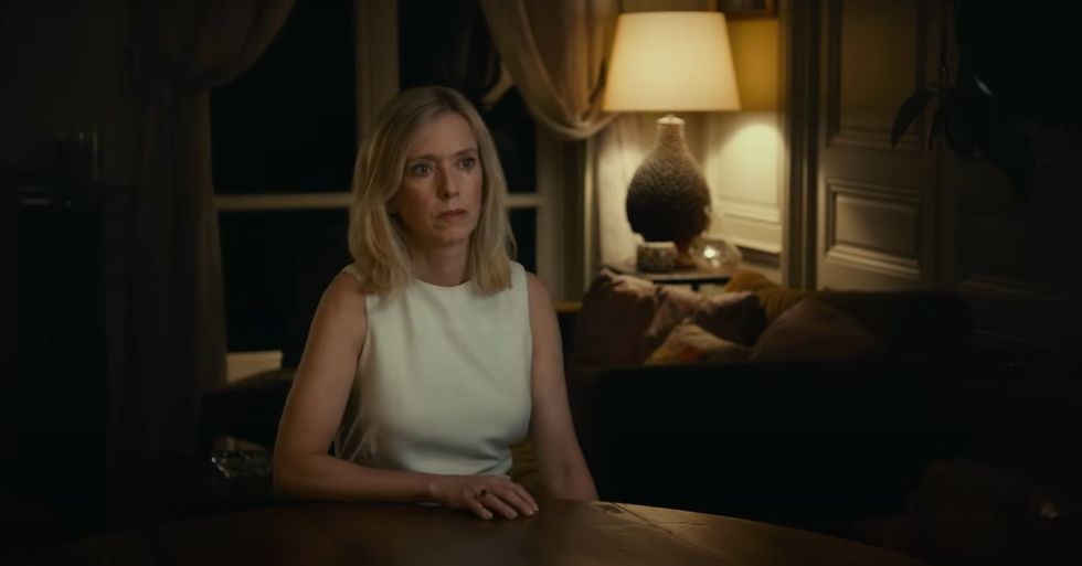 A woman sitting on a table in a room with little light