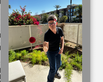 a person playfully punching a red boxbollen ball outdoors on a sunny day, part of a good housekeeping review of the punch ball game