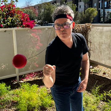 testing Boxbollen for the Good Housekeeping Institute a person playfully punching a red boxbollen ball outdoors on a sunny day, part of a good housekeeping review of the punch ball game