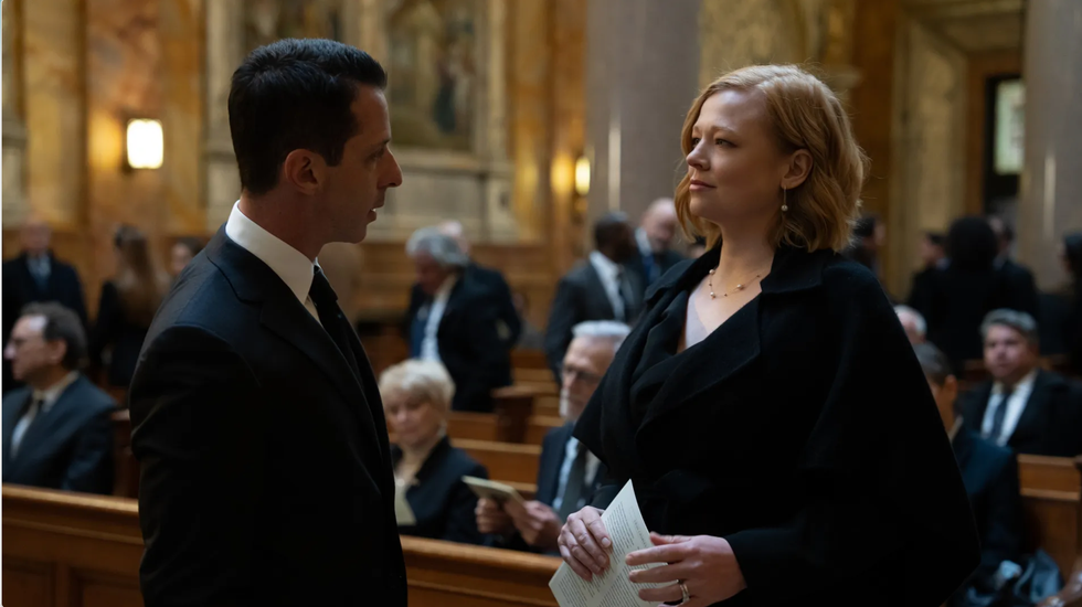 conversation between two individuals in a formal setting surrounded by attendees