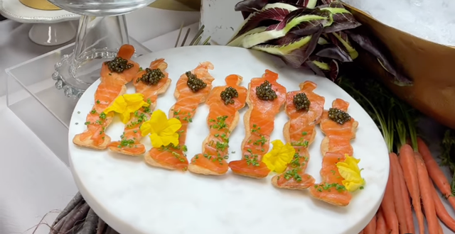 artfully arranged salmon pieces shaped like figures on a marble platter