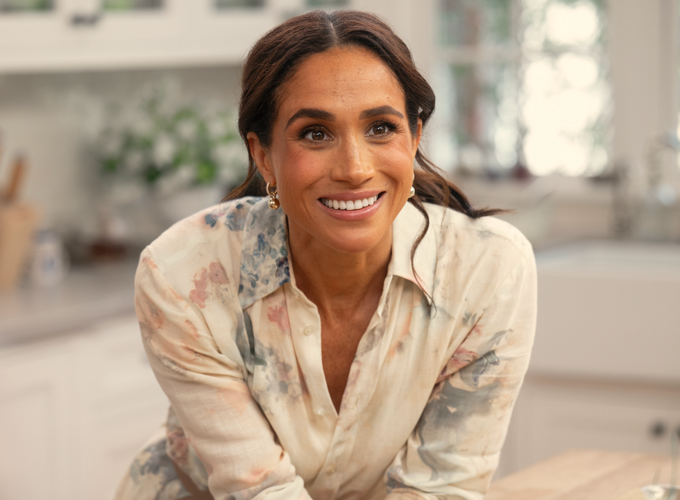 woman in a floral blouse leaning on a kitchen counter
