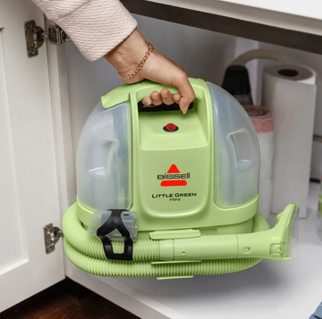Bissell Little Green Mini Portable Carpet Cleaner a person carrying the bissell little green mini portable carpet cleaner and storing it in a cabinet under the kitchen sink