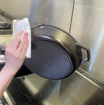 wiping oil on the outside of a cast iron pan to season it