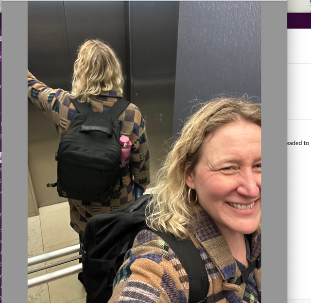 a woman wears a black travel backpack in an elevator