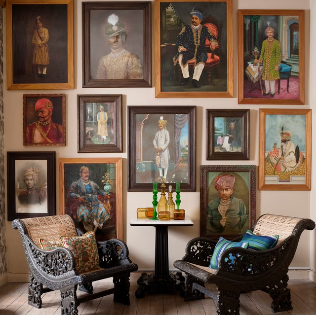 collection of portraits arranged on a wall with decorative seating and a table