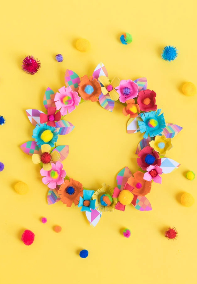 colorful wreath made from paper flowers and pompoms on a yellow background