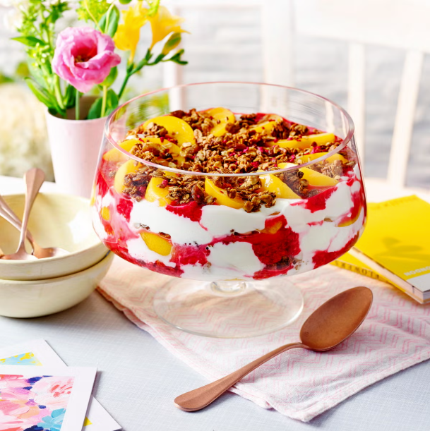 layered dessert in a glass bowl with granola and fruit