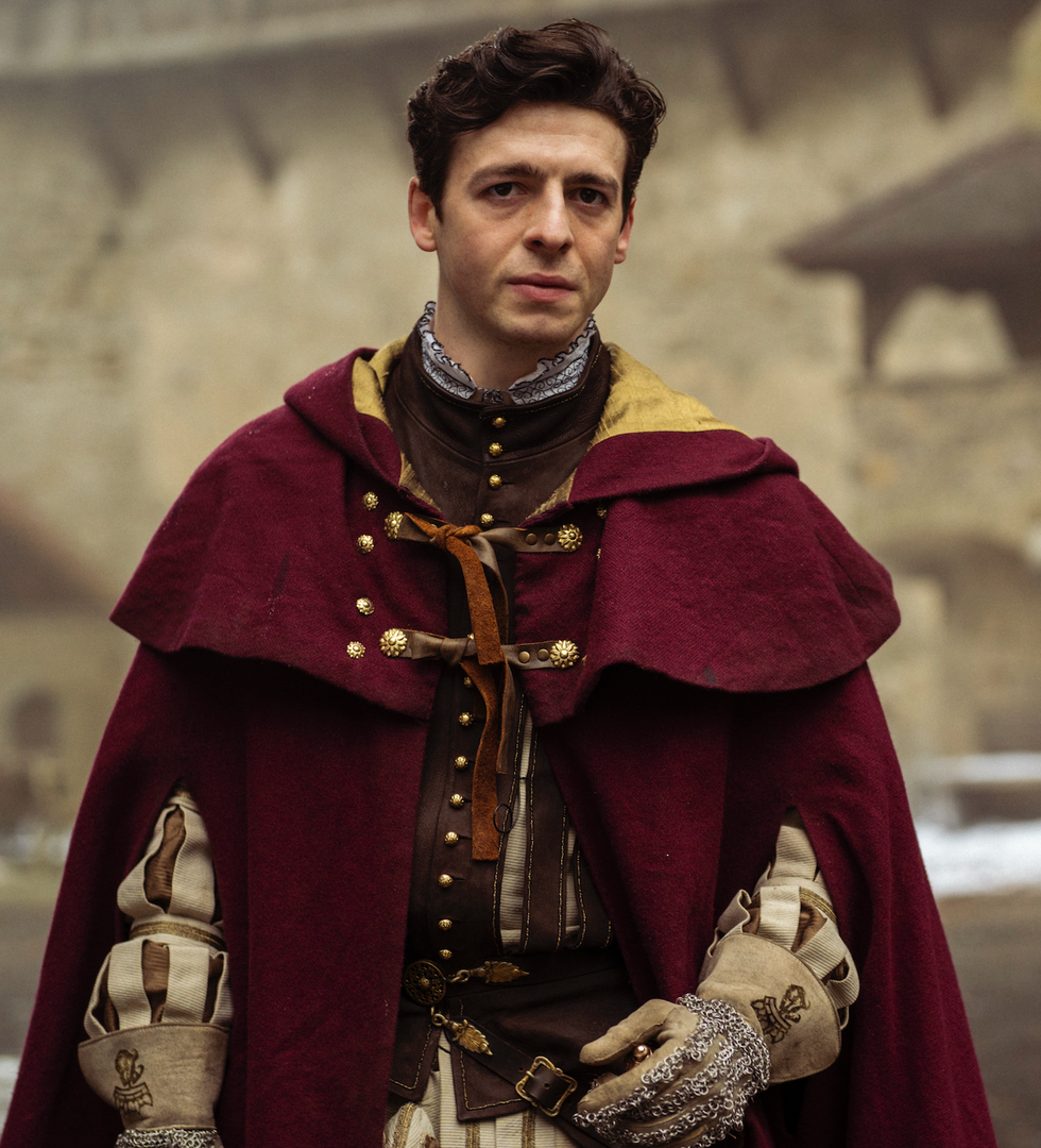 individual dressed in historical attire with a burgundy cloak